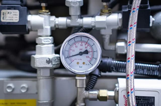 Pressure gauge on heating system pipework with valves and a braided hose