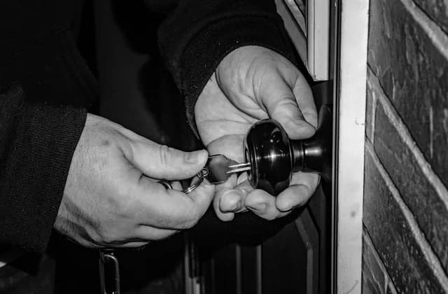 Manos abriendo una puerta con llave, en blanco y negro