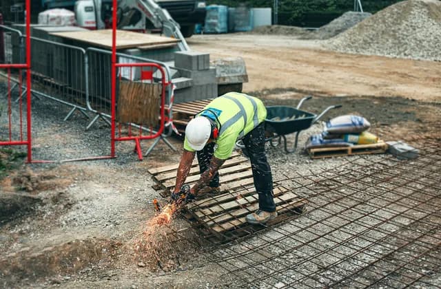 A construction worker in a hi-vis vest cutting steel reinforcement on site