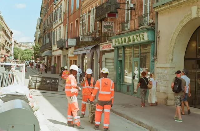 Des ouvriers en gilet orange sur un chantier de voirie en centre-ville
