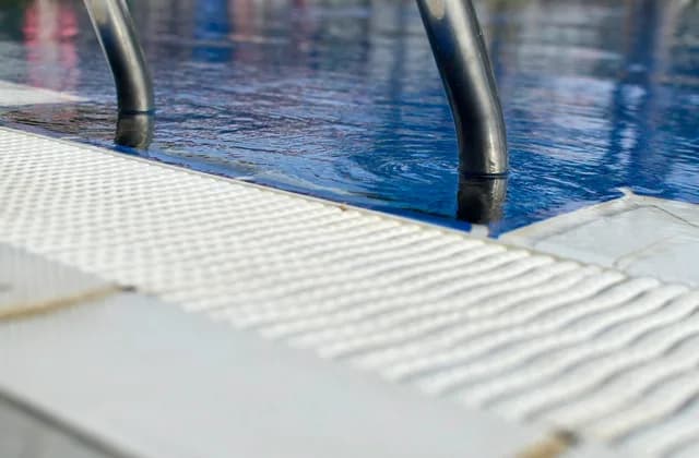 Échelle et bord d'une piscine à l'eau bleue