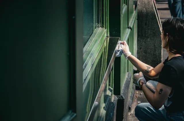 Person arbeitet an einem geöffneten Fensterflügel