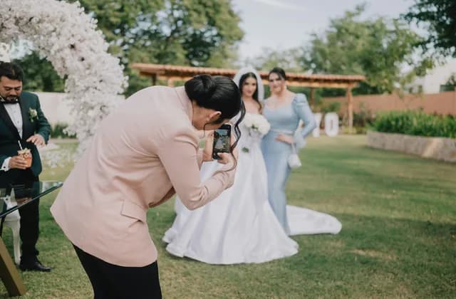 Fotógrafa tomando fotos a una novia en un jardín durante una boda