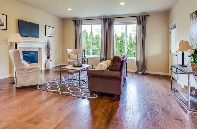 Living room with hardwood floors, a sofa, armchairs and a fireplace