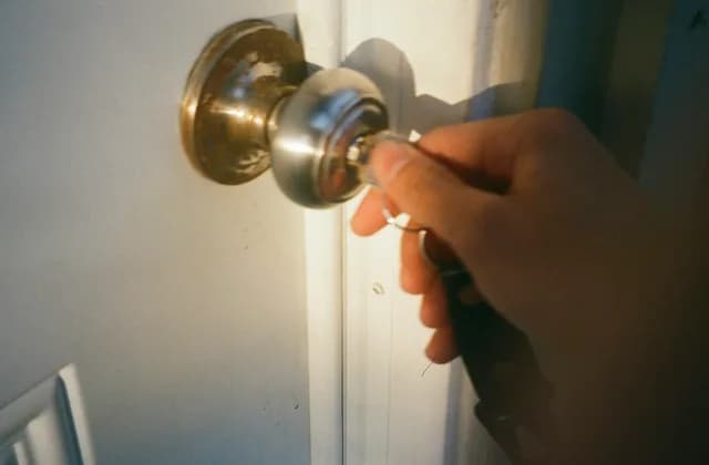 Hand turning a key in a brass door knob
