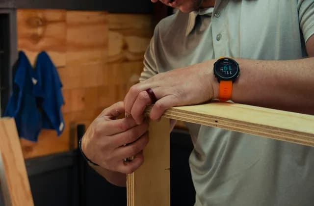 Carpenter's hands checking a wooden rail in a workshop