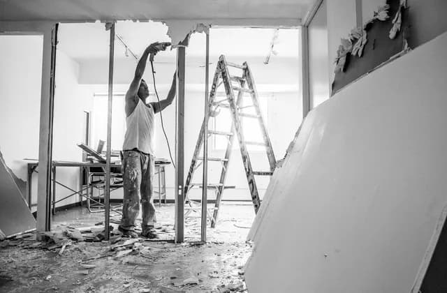 Builder working on the stud frame of a stripped-out room during a renovation