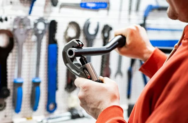Plumber holding a pipe wrench in front of a tool wall