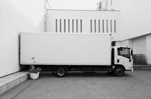 Plain white box truck parked beside a building