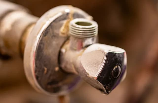 Llave de paso antigua de un grifo con restos de cal y corrosión, en primer plano