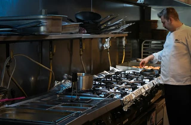 A chef working the range in a commercial kitchen