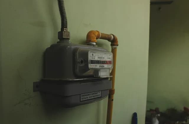 Medidor de gas montado en una pared verde claro con su tubería