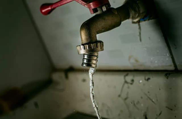 Llave de agua vieja goteando en un rincón