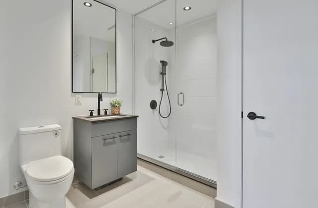 Baño con mampara de ducha de cristal, lavabo y plato de ducha a ras de suelo
