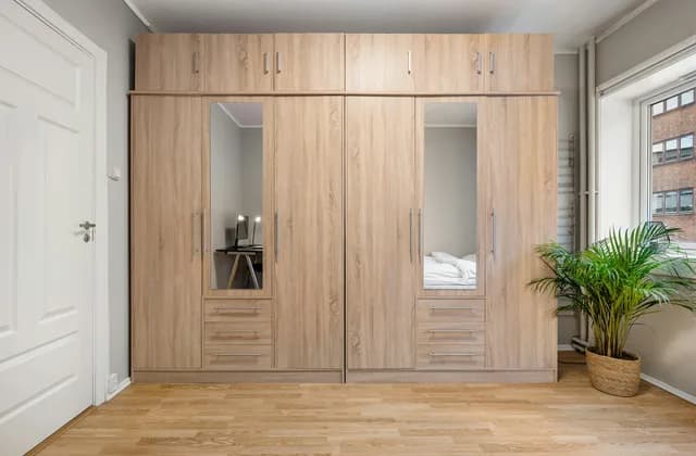 Armario empotrado de madera con puertas de espejo en un dormitorio