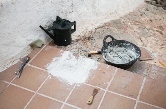 Outils de carreleur et mortier posés sur un sol carrelé
