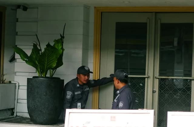 Un agent de sécurité en uniforme surveillant l’entrée d’un bâtiment
