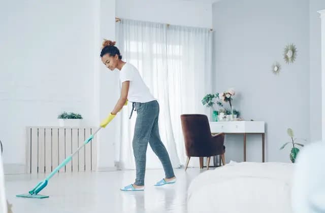 Persona de limpieza trapeando el piso de una sala