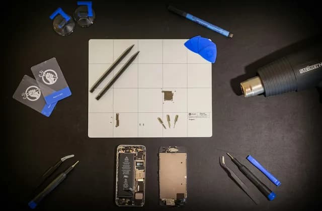 Bancada de conserto de celular com ferramentas, tela e peças