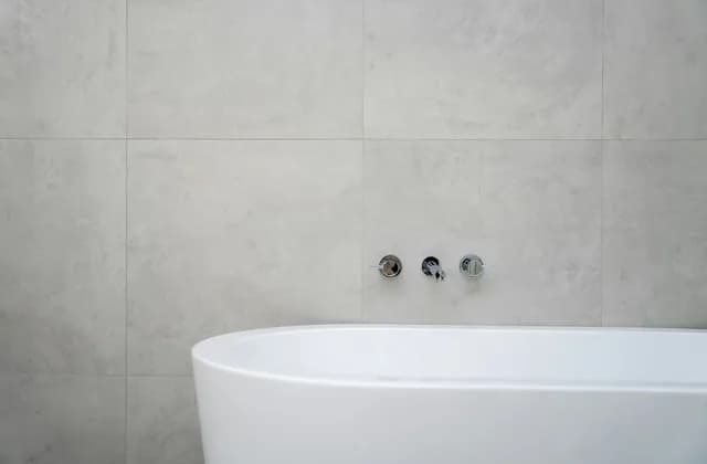 Badezimmer mit großformatigen grauen Wandfliesen und freistehender Wanne