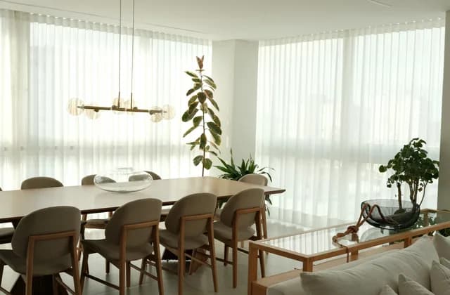 Sala de jantar com cortinas claras do teto ao chão
