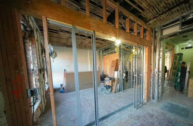 Sökülmüş tavan ve duvarlar arasında metal karkasla yeniden bölümlenen, tadilatı süren bir iç mekân