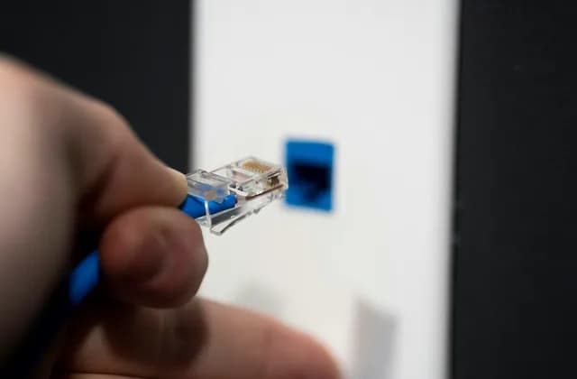 Elde tutulan mavi ethernet konektörünün duvardaki prize takılması
